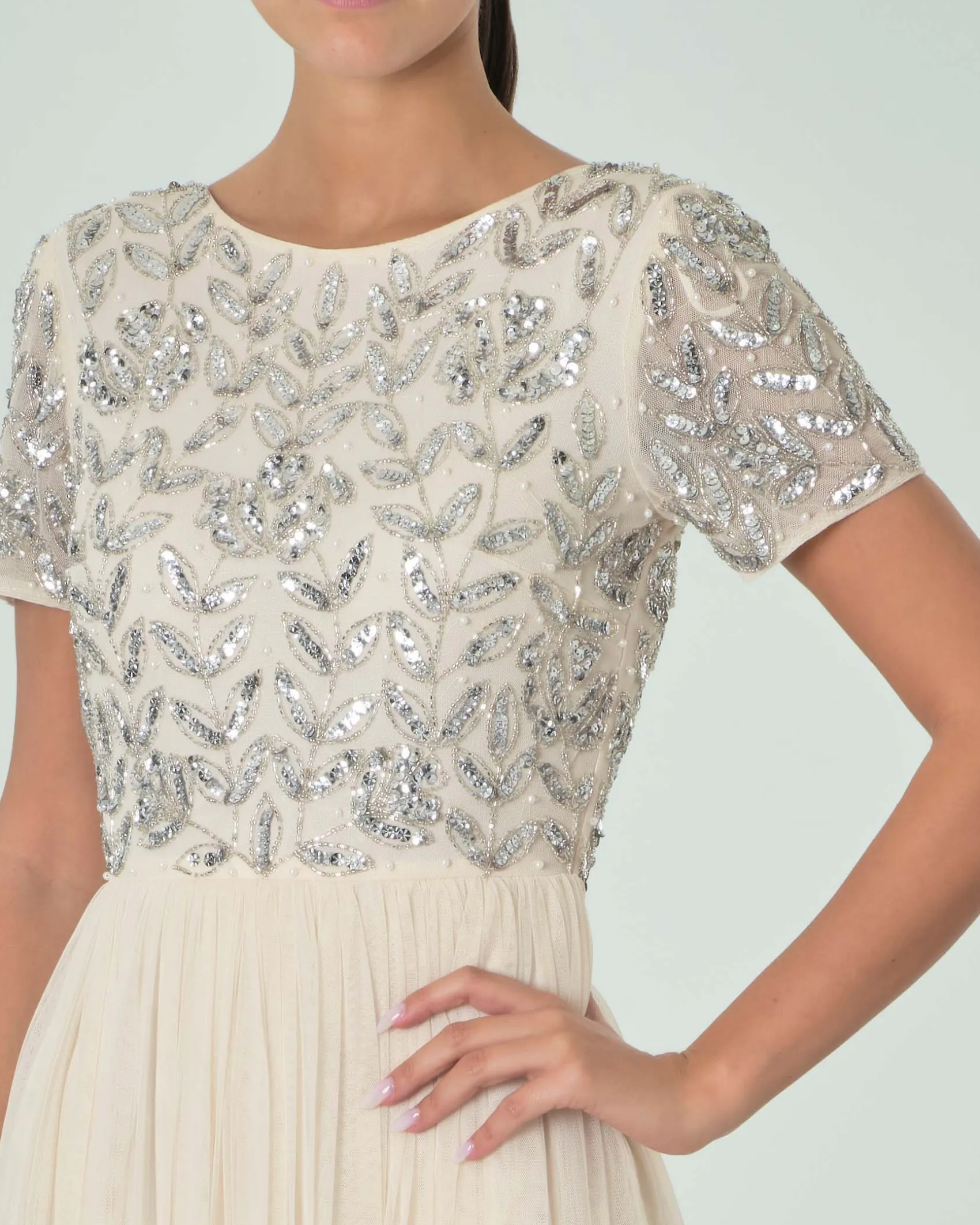 Abito lungo color avorio in tulle con corpetto a maniche corte ricamato in paillettes e perline argento