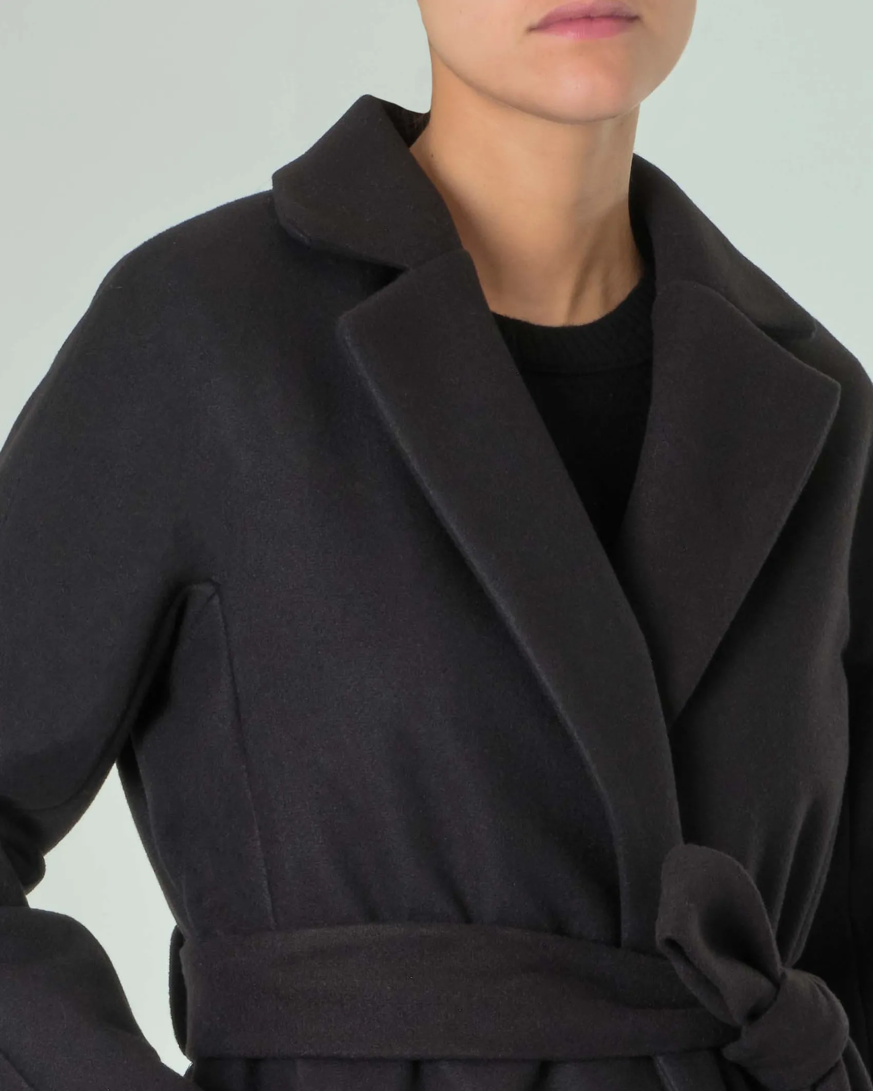 Cappotto nero in panno con cintura in vita e scollo a rever