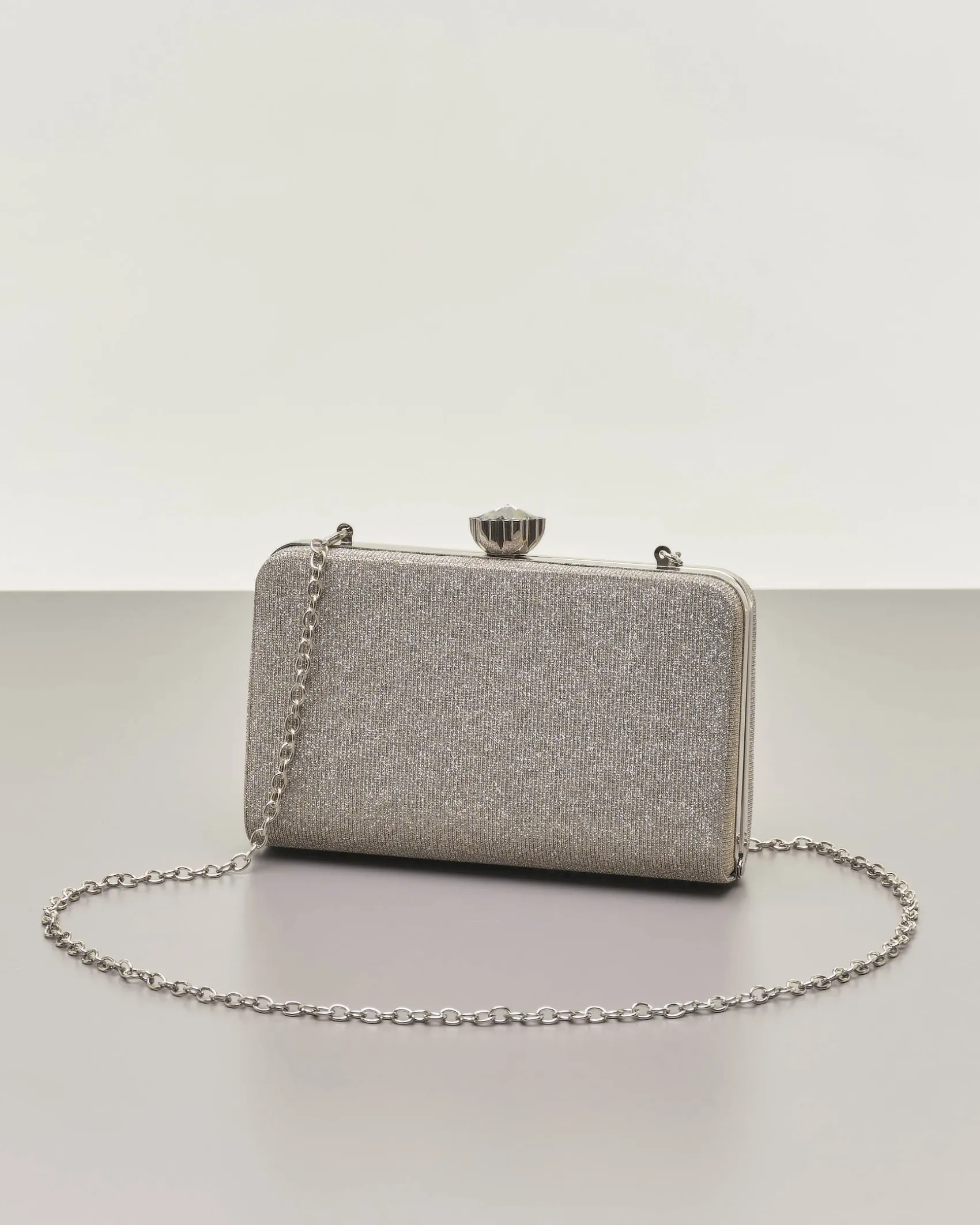 Clutch rigida color grigia in lurex con strass tono su tono applicati sul davanti e chiusura a gioiello a scatto