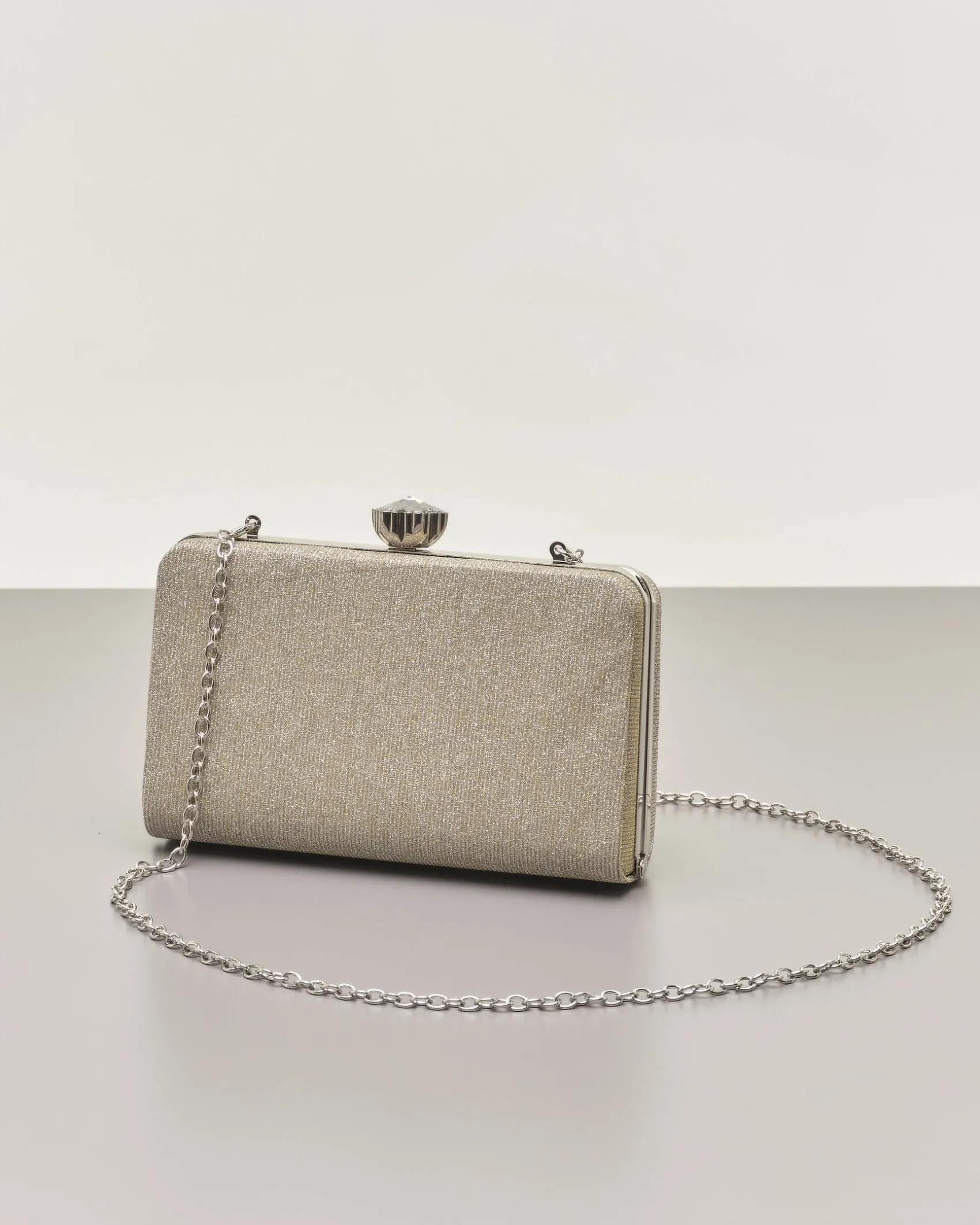 Clutch rigida color oro in lurex con strass tono su tono applicati sul davanti e chiusura a gioiello a scatto